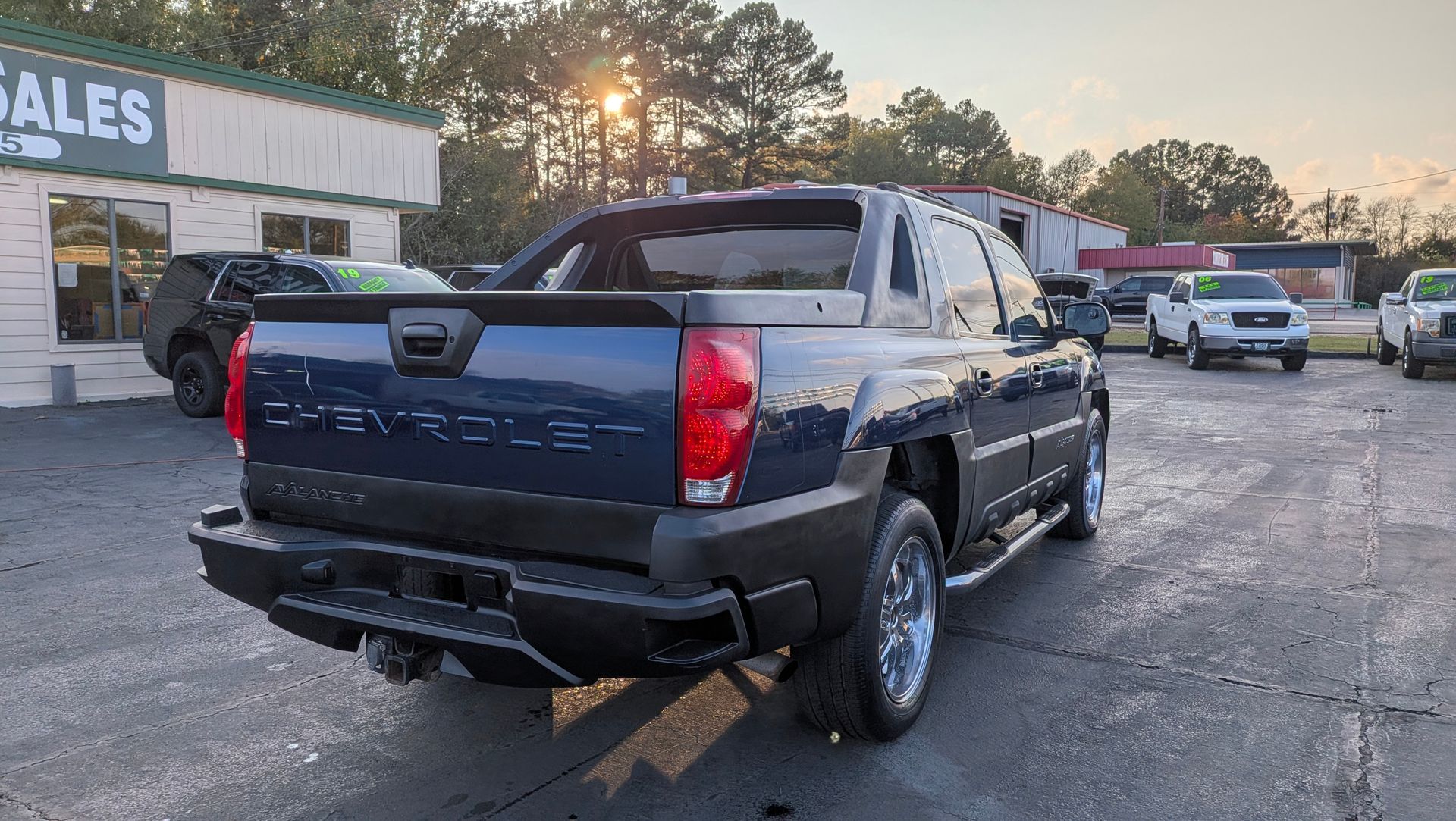 Dark blue Chevrolet Avalanche truck parked at a car dealership.