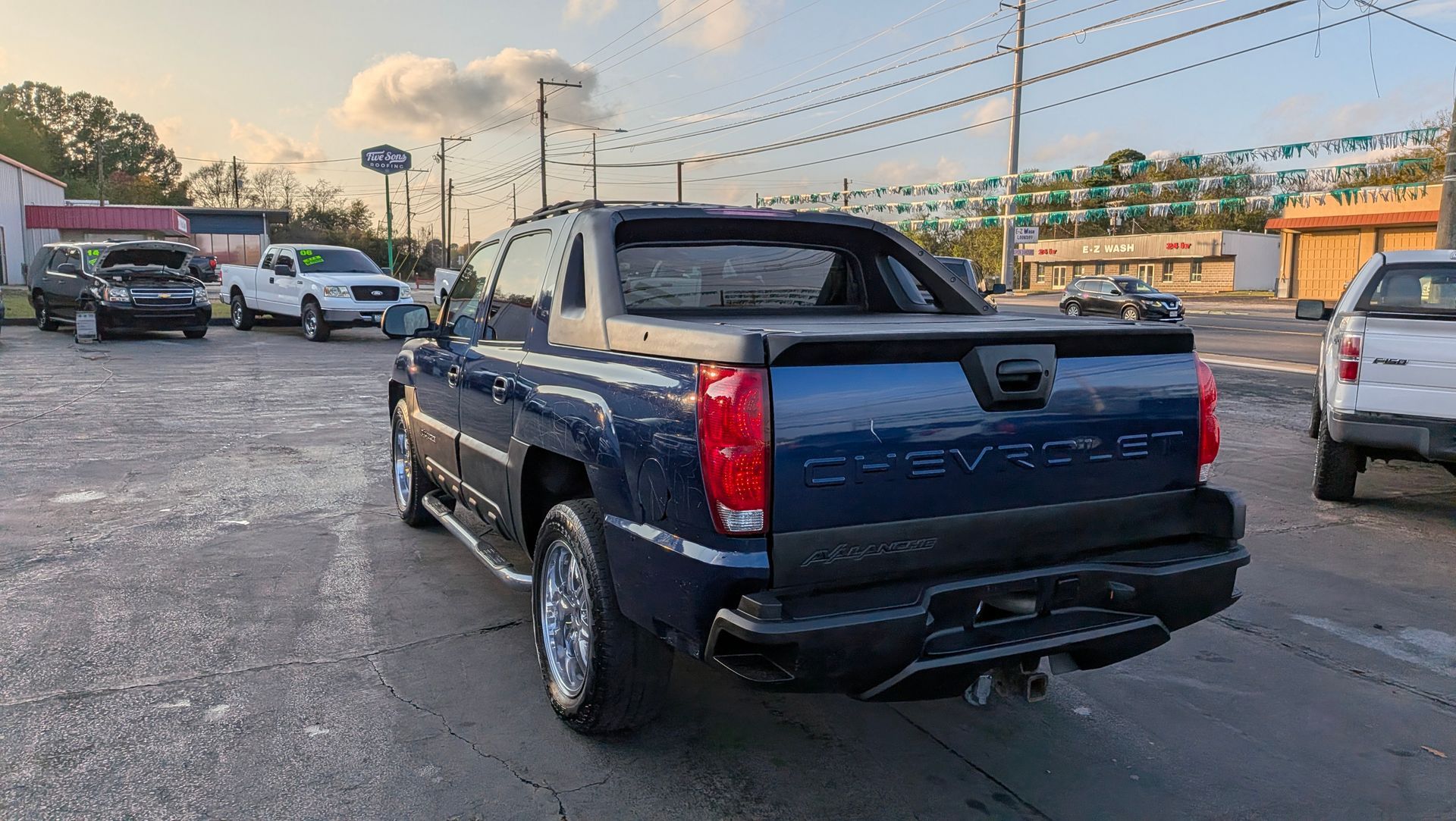 Blue Chevrolet Avalanche truck, parked on asphalt lot, rear view.