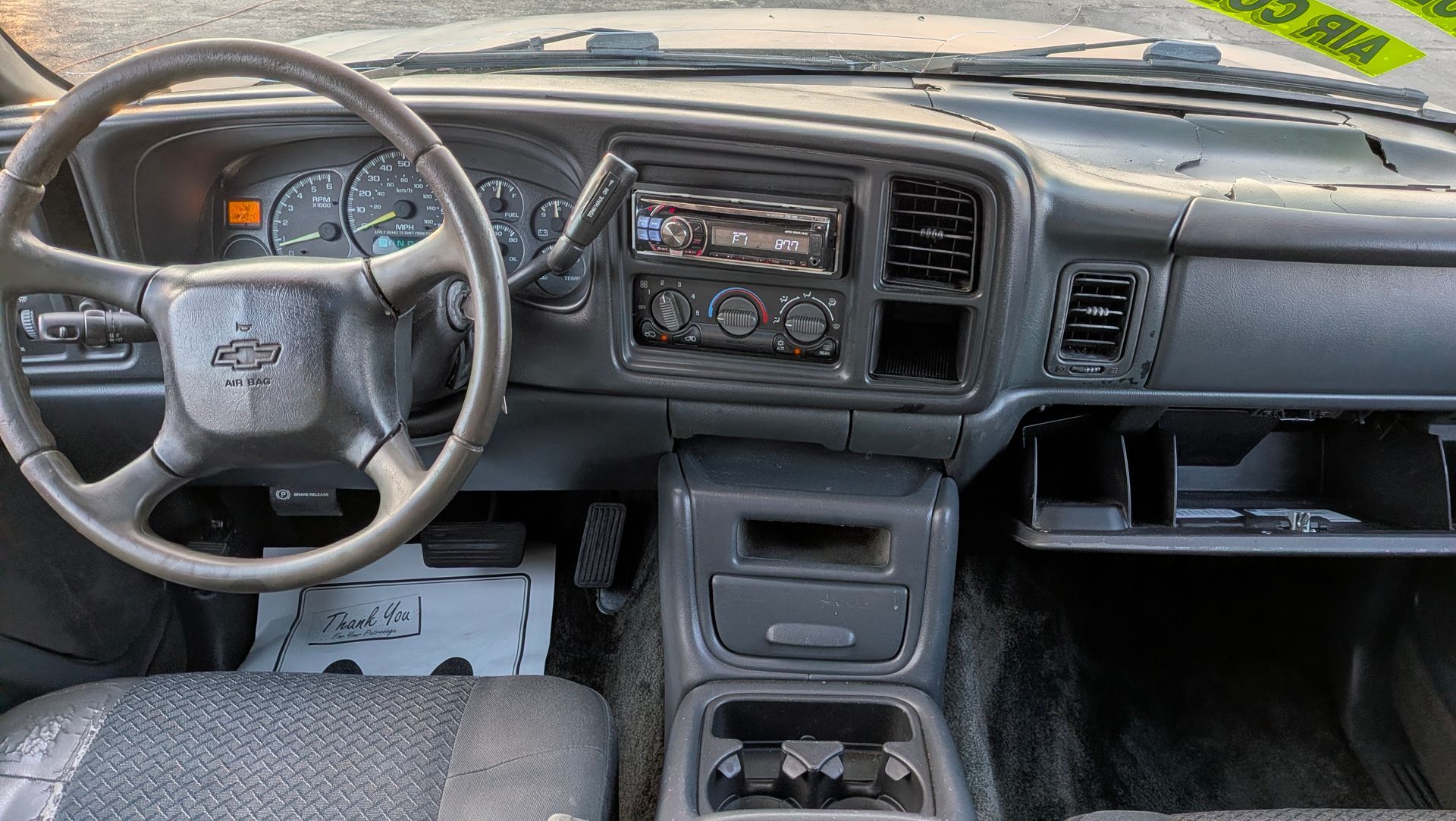 Interior view of a gray Chevrolet truck dashboard, including steering wheel, gauges, radio, and glove compartment.