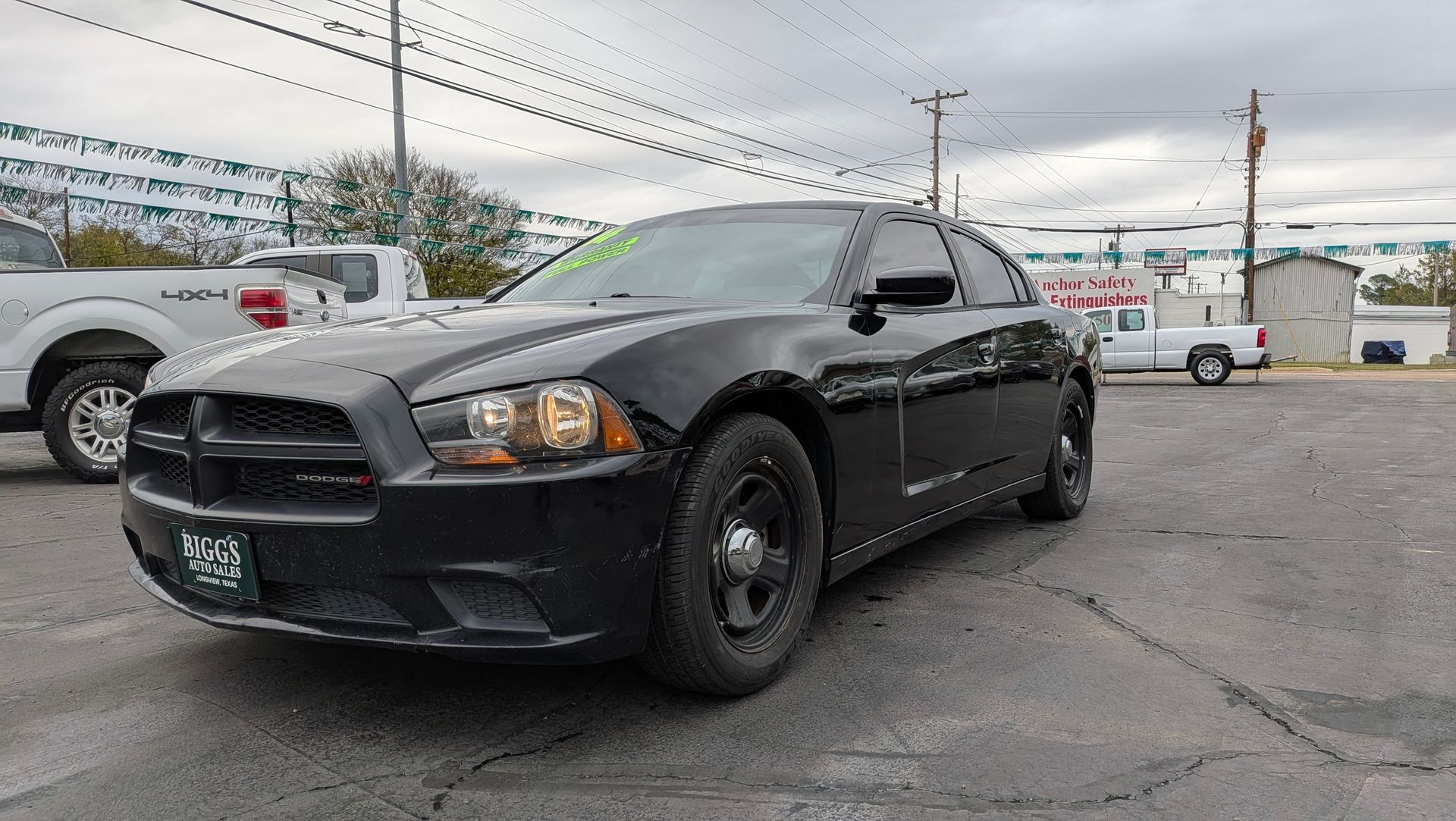 Black Dodge Charger police car parked outside on a cloudy day.