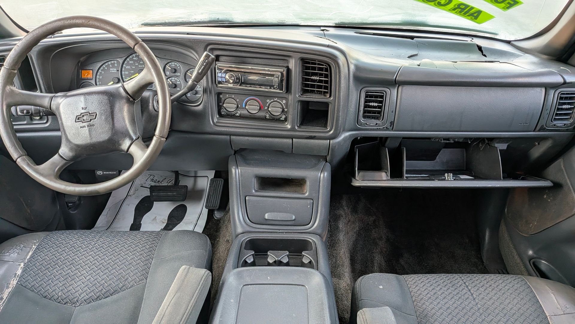 Dashboard of a gray pickup truck, including the steering wheel, console, and glove compartment.