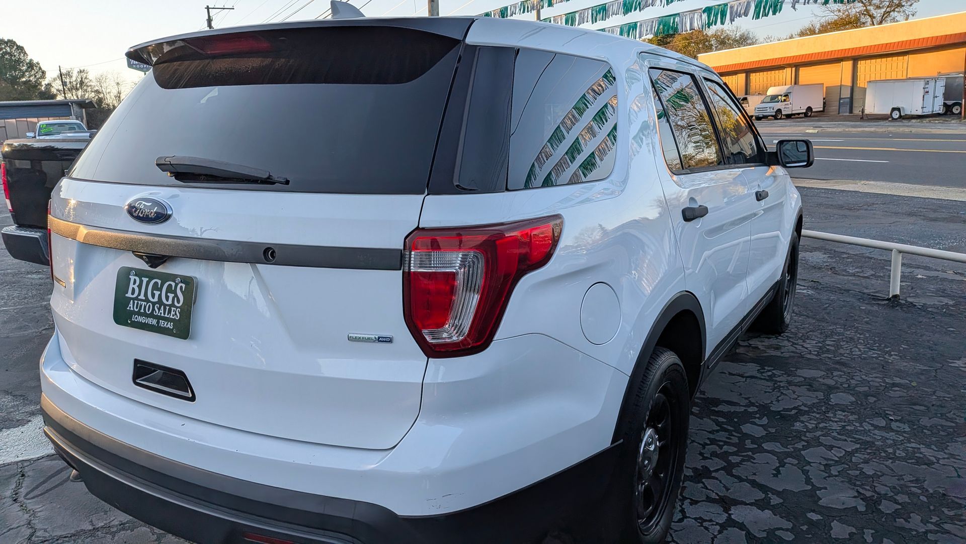White Ford Explorer SUV, rear view, in a parking lot. Tail lights and license plate visible.
