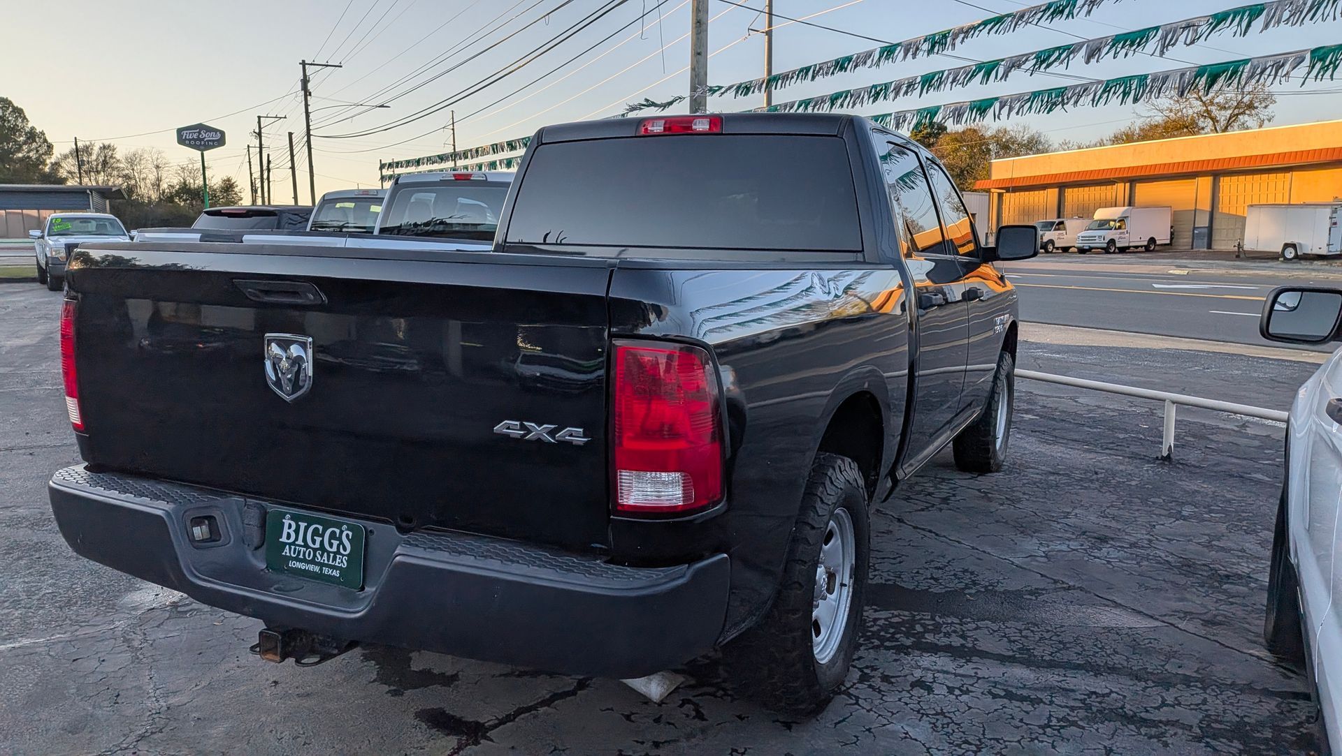 Black Ram 1500 truck with 4x4 emblem, parked in a lot. The truck bed is covered.