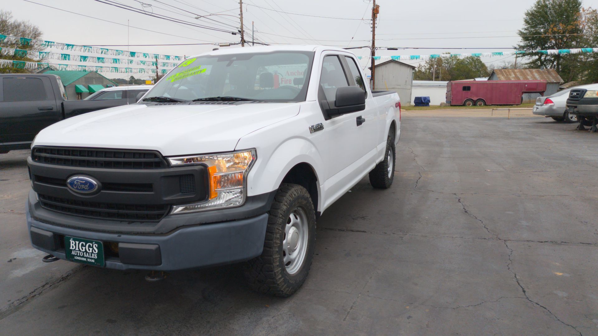 White Ford F-150 truck parked in a car lot on a cloudy day.