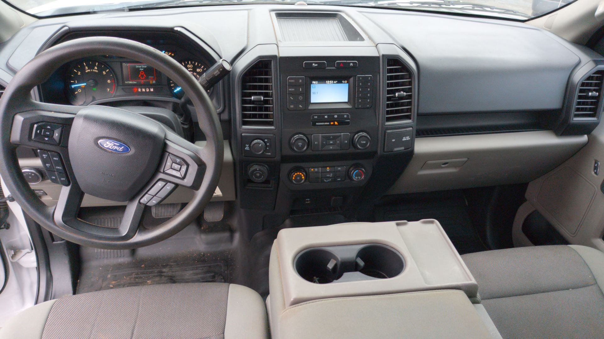 Interior of a Ford F-150 truck, showing dashboard, steering wheel, center console with cup holders, and seats.