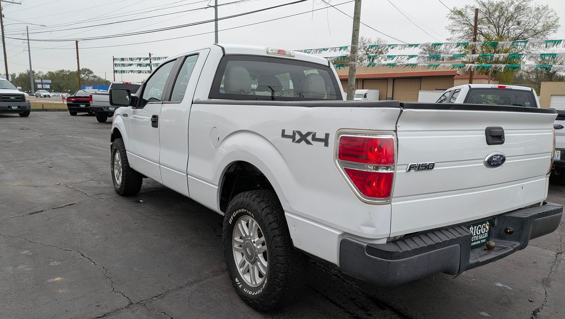 White Ford F-150 truck with 4x4 emblem, parked on asphalt in a lot.