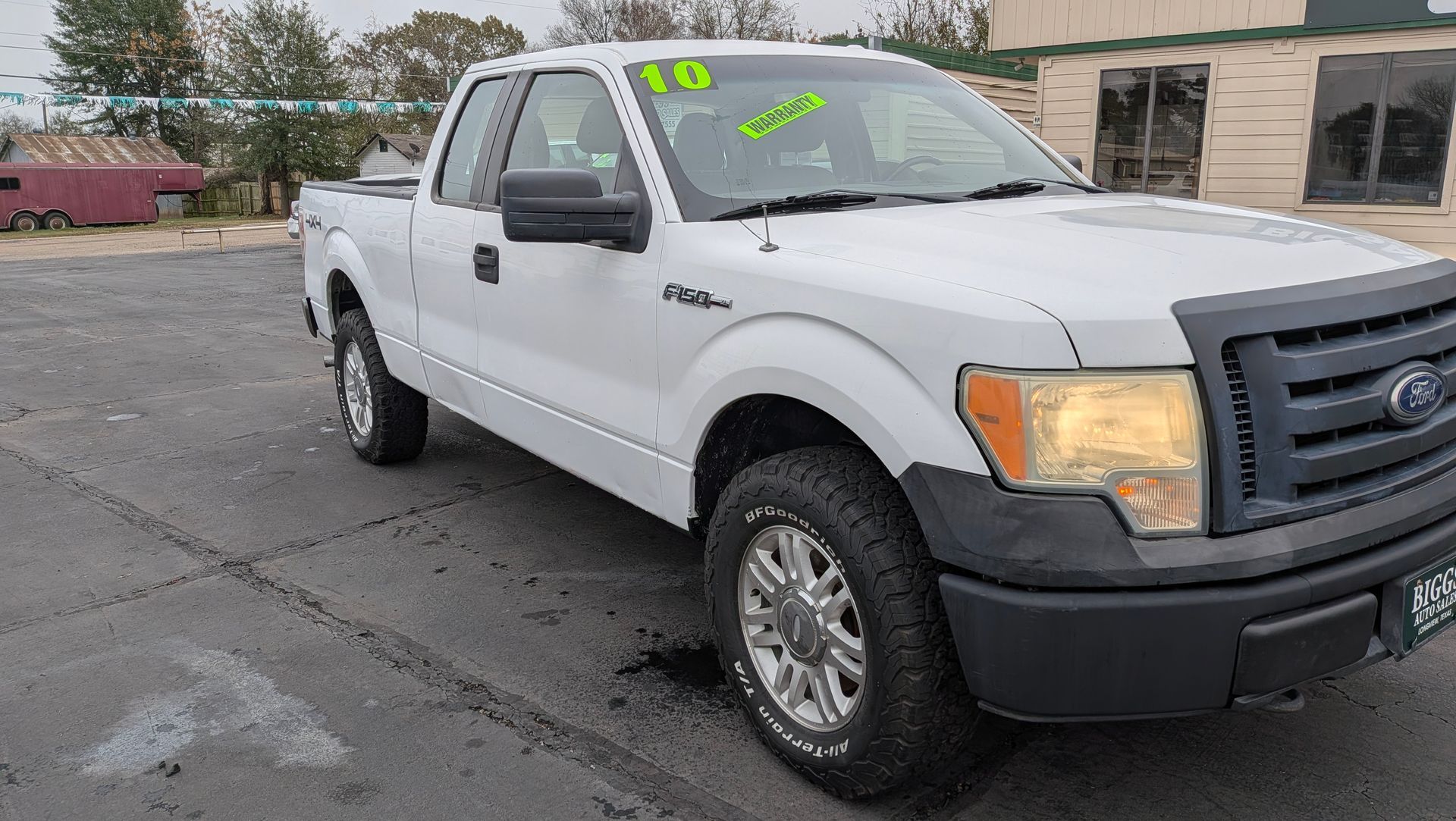 White Ford F-150 pickup truck parked on asphalt in front of a building.