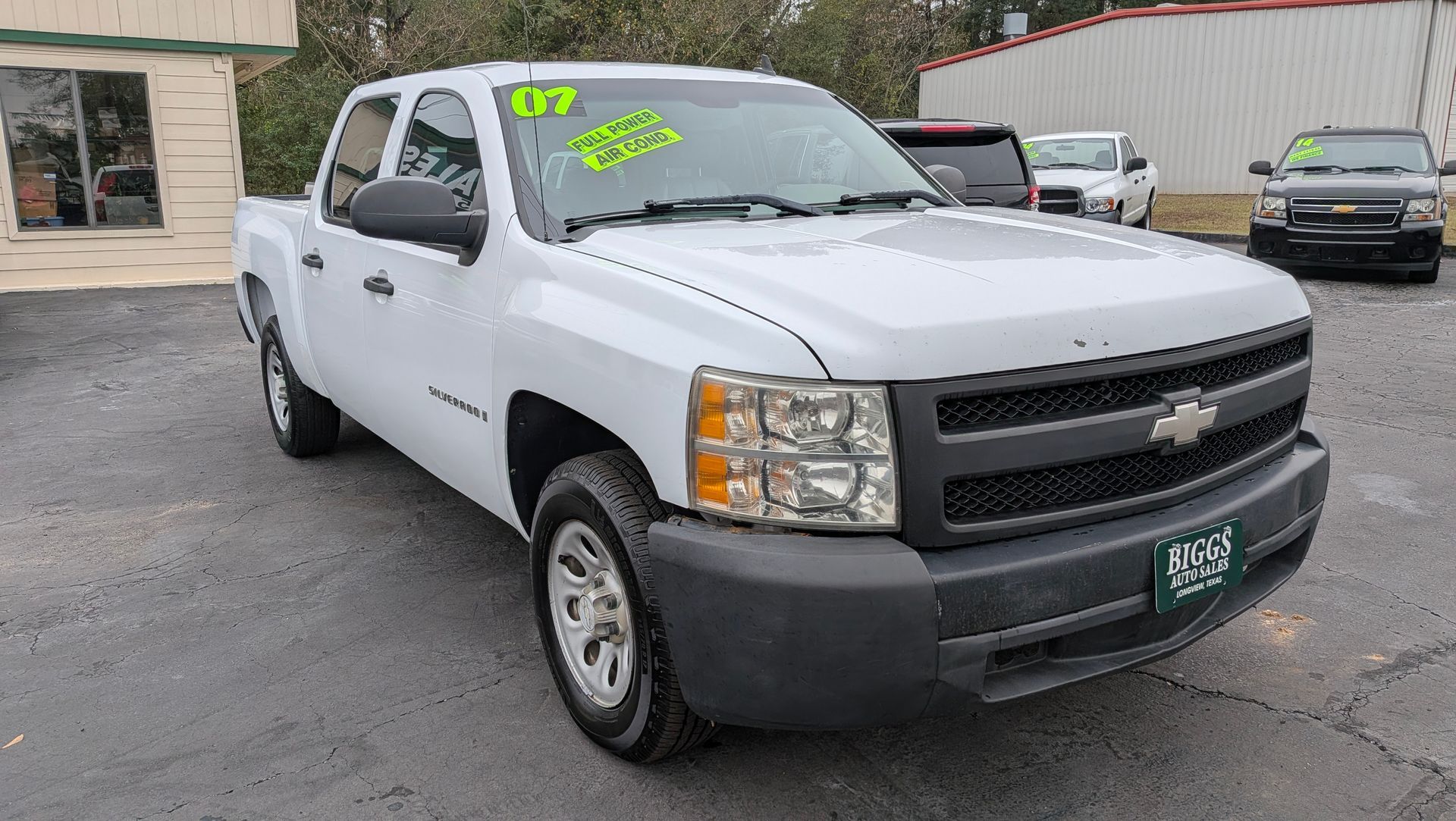 White Chevrolet Silverado pickup truck parked outside a dealership.