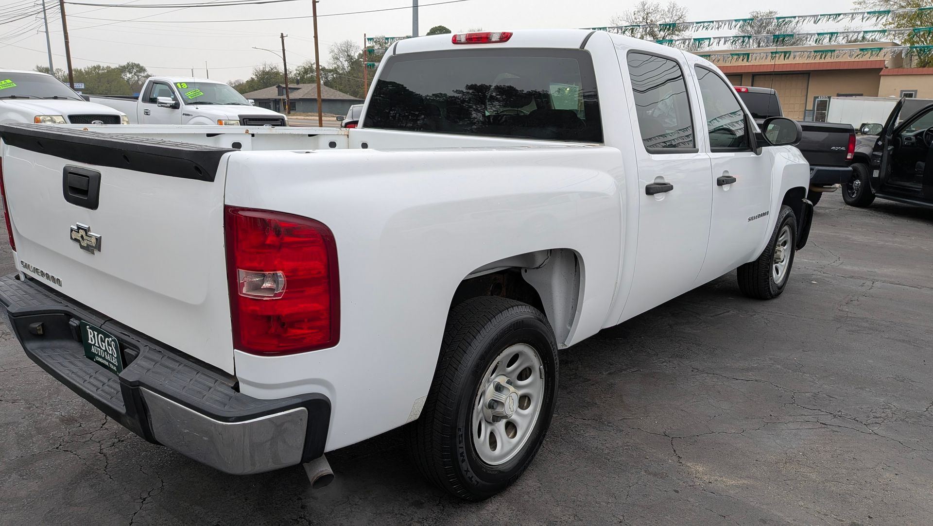 White Chevrolet Silverado pickup truck parked outside a dealership.