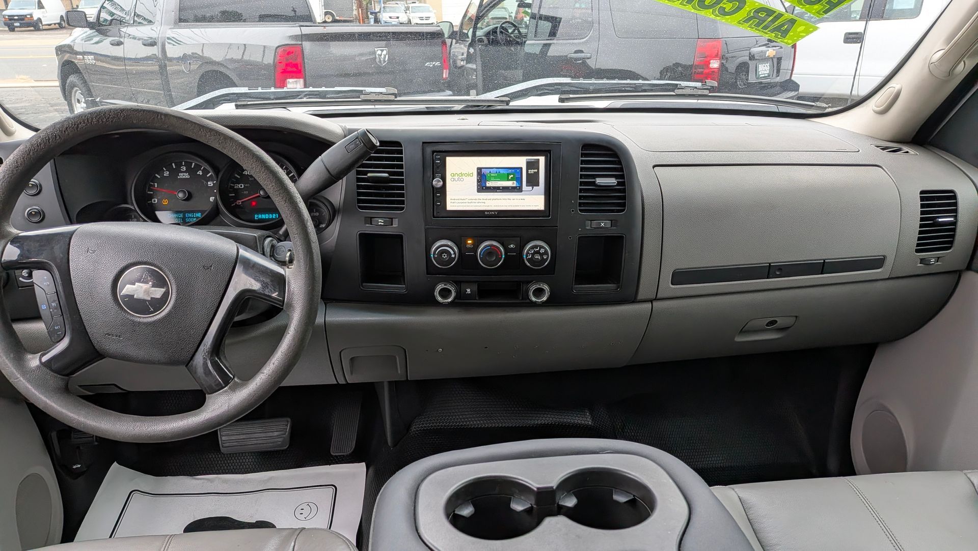 Interior of a gray Chevrolet truck showing the dashboard, steering wheel, and console with cup holders.