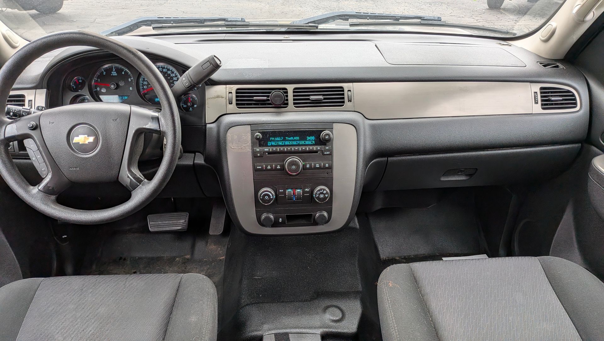Interior of a Chevrolet truck. Dashboard with steering wheel, radio, air vents, and seats.