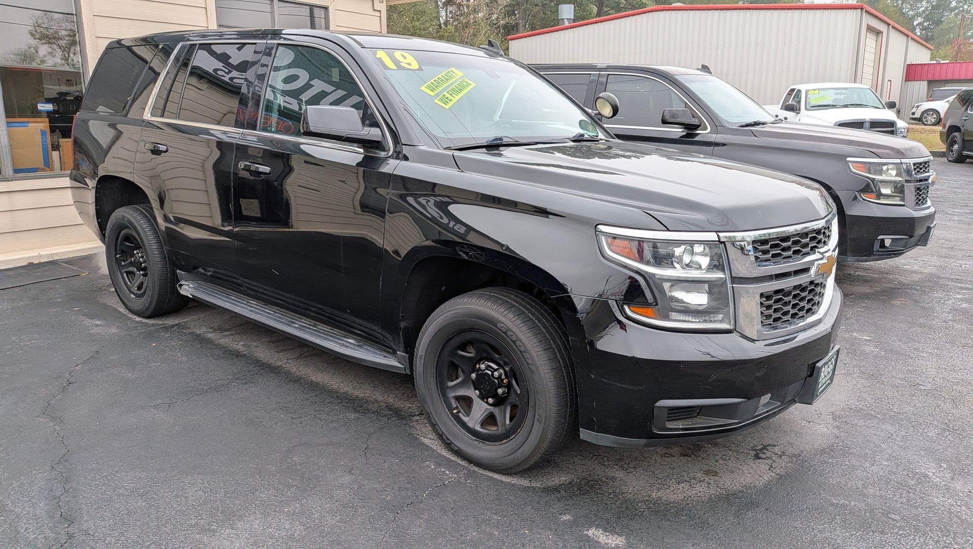 Black Chevrolet Tahoe SUV, parked in front of a building, with another similar vehicle in the background.