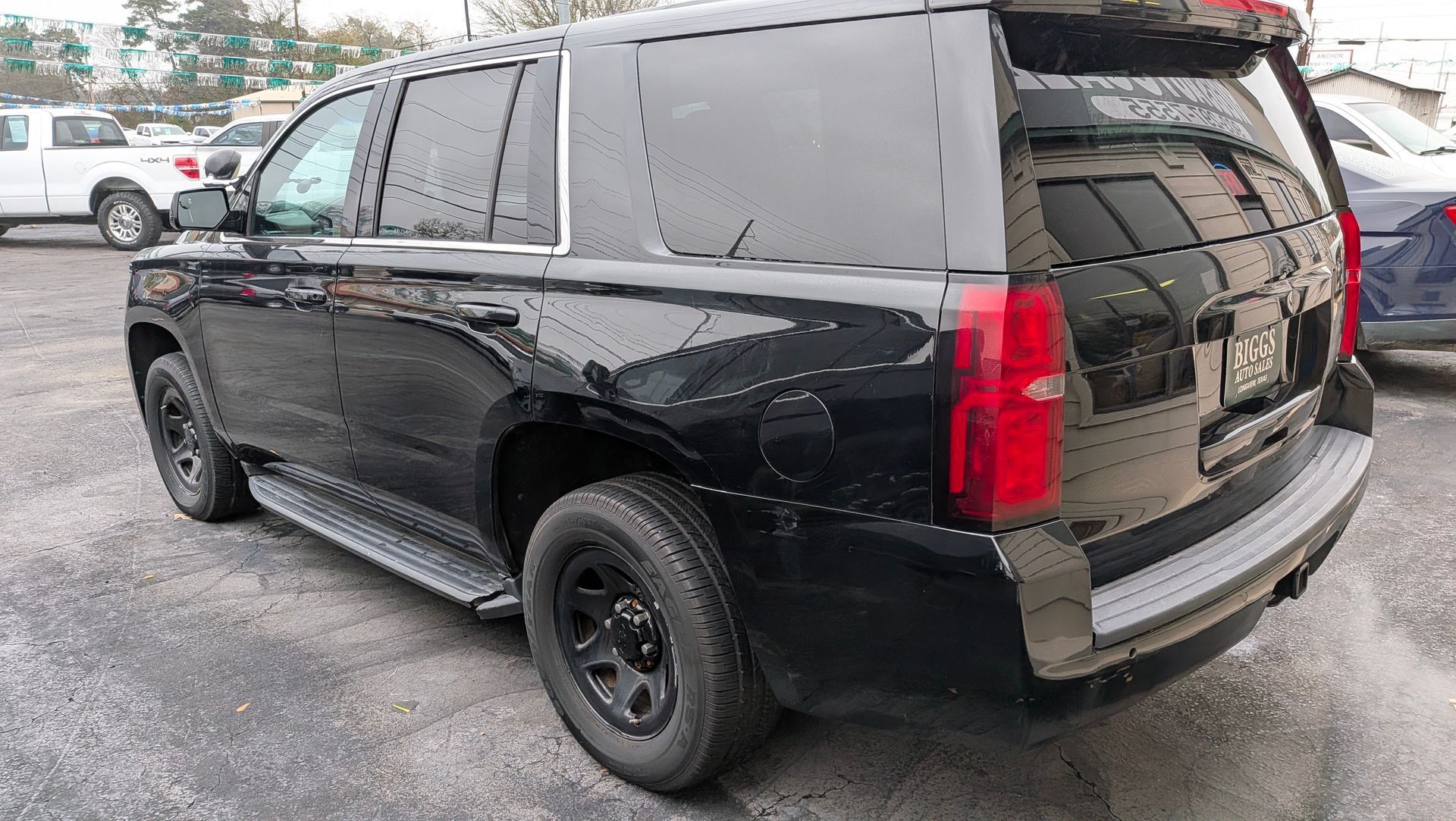 Black SUV parked on a gray lot, with tinted windows and black wheels.