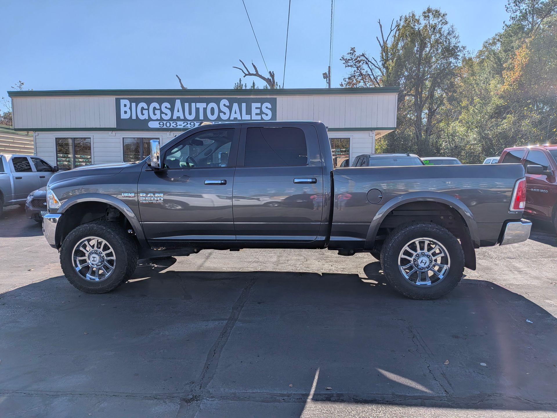 Gray Ram pickup truck parked in front of Biggs Auto Sales building on a sunny day.