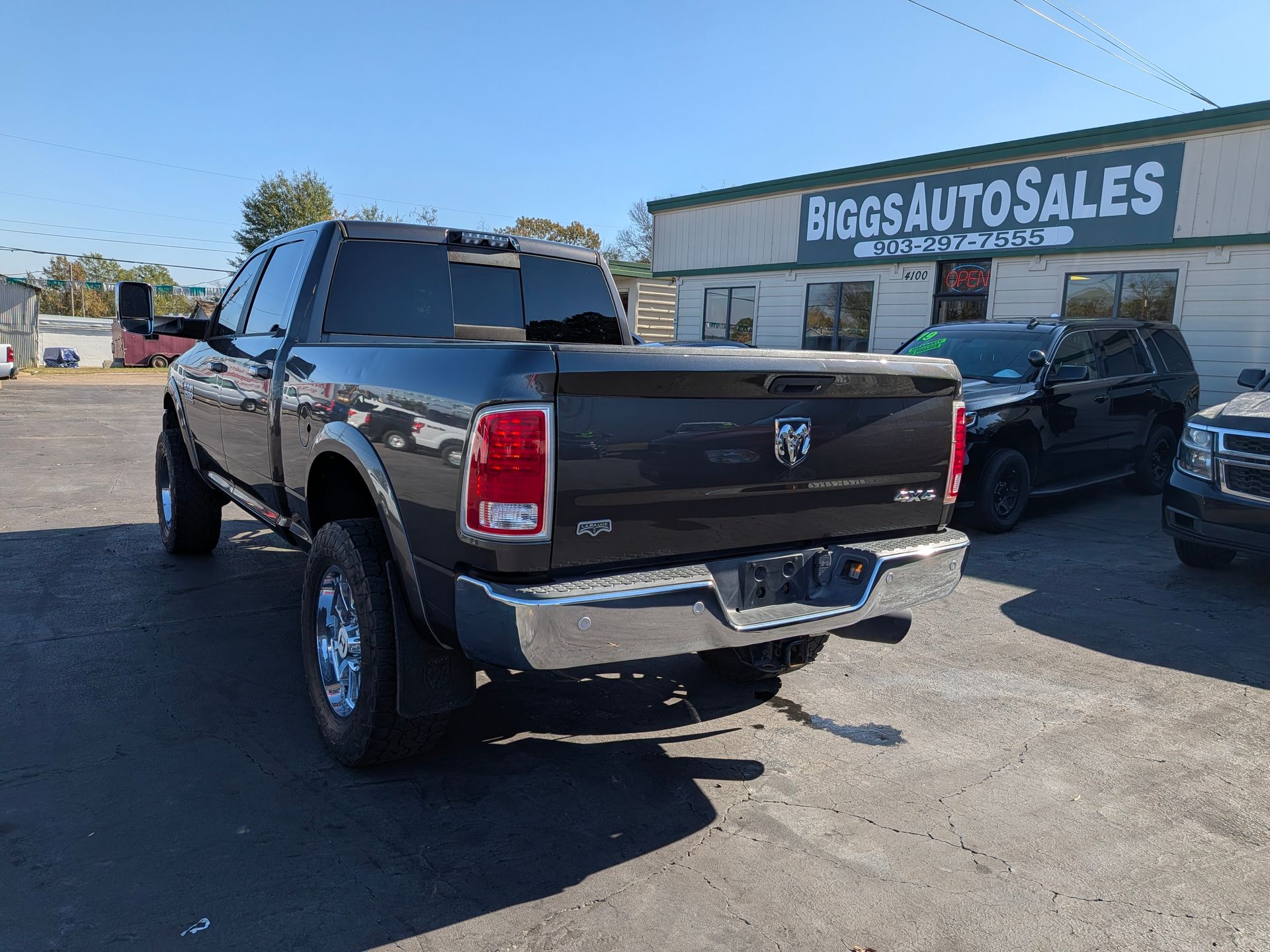 Black Dodge Ram truck parked in front of Biggs Auto Sales building on a sunny day.