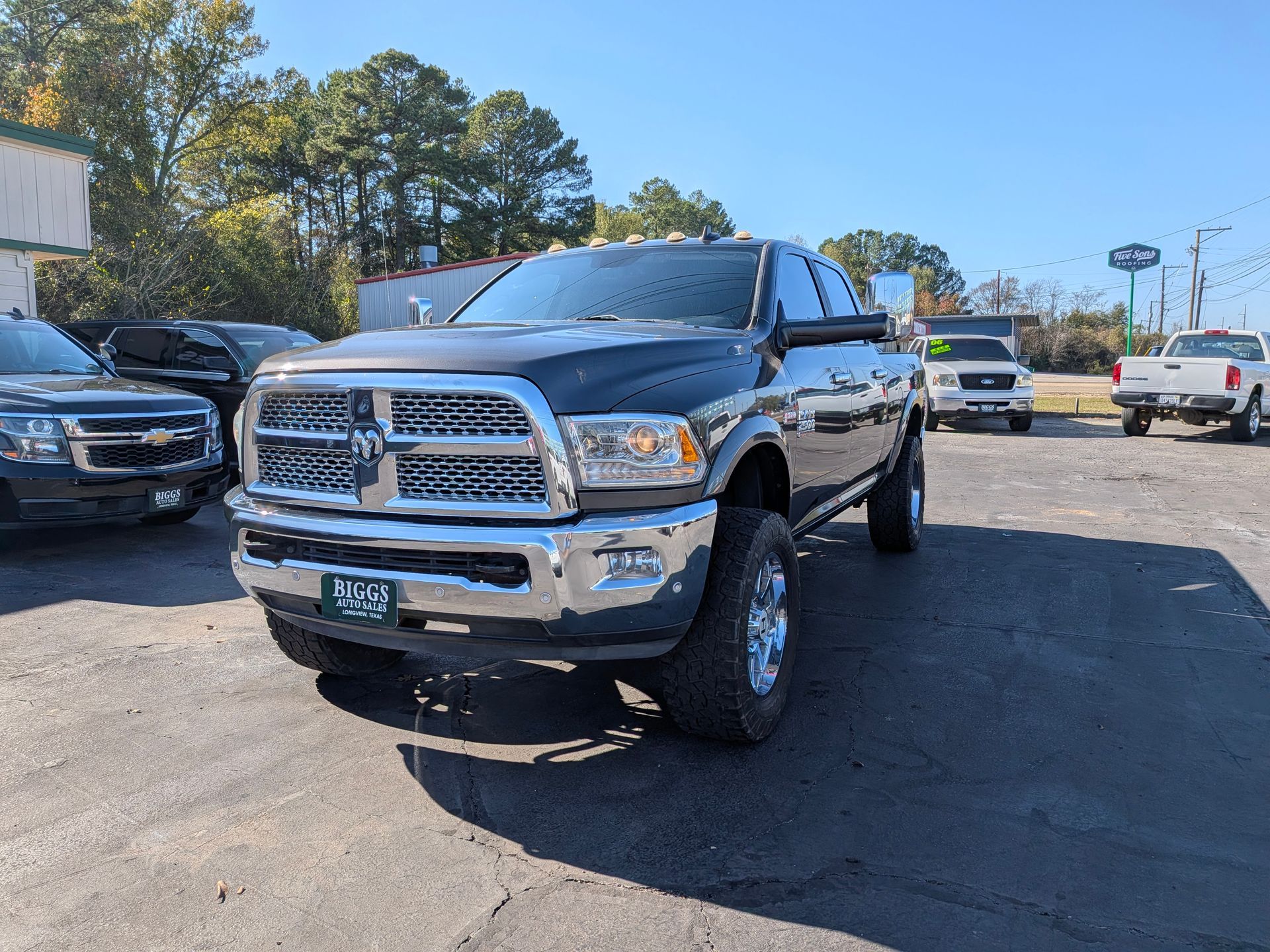 Black Dodge Ram truck parked on asphalt lot, sunny day.