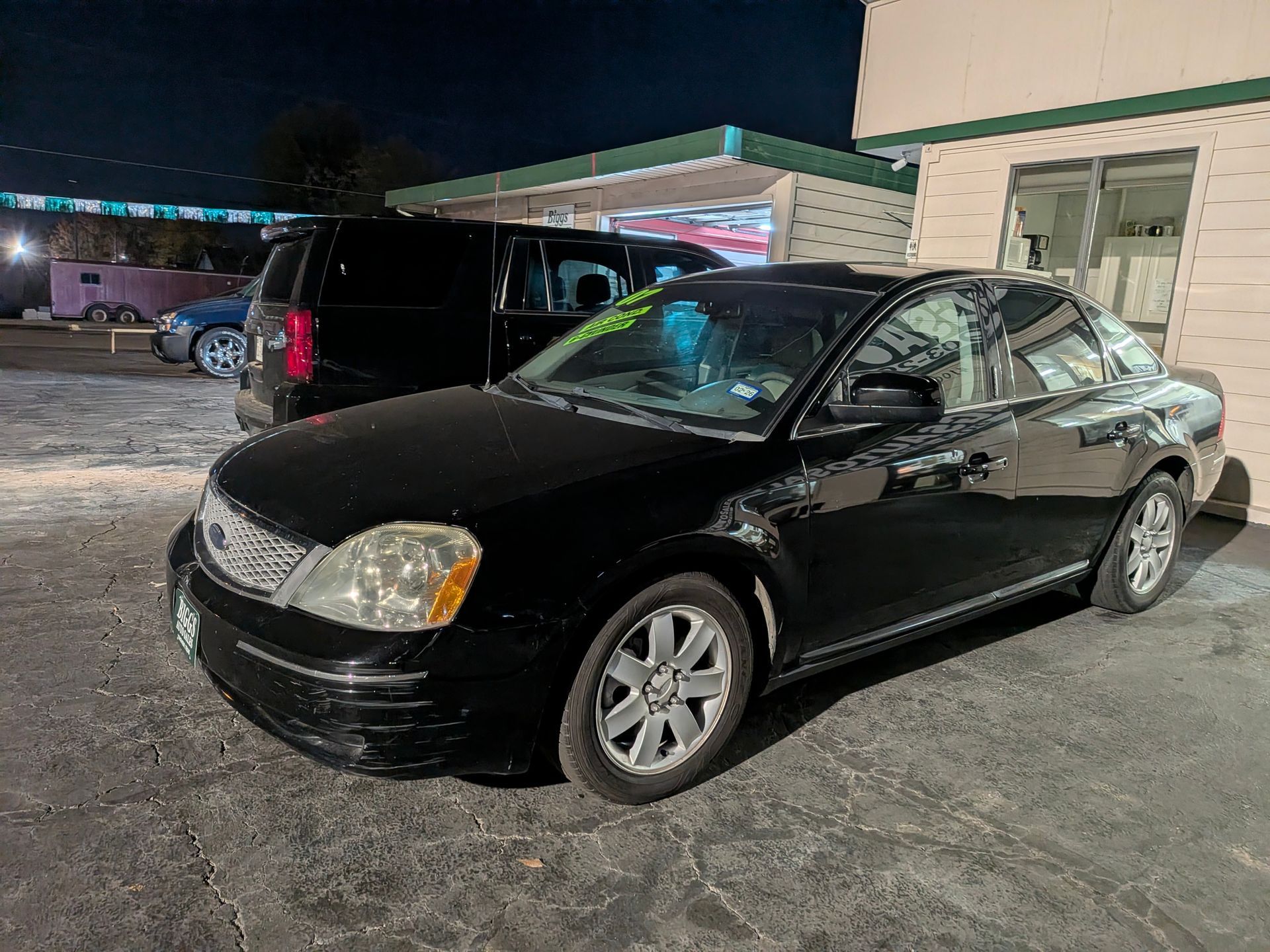 Black Ford sedan parked in front of a building at night.