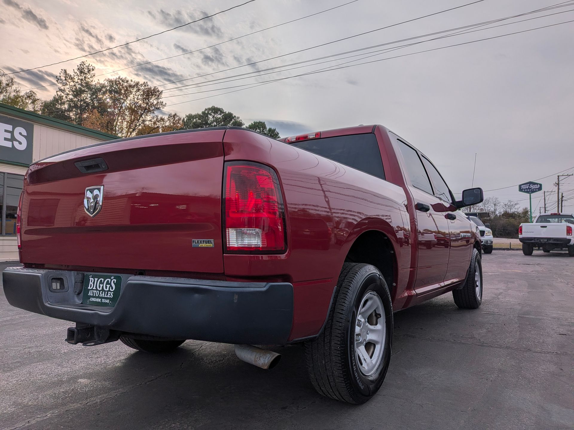 Red Dodge Ram pickup truck parked on asphalt, cloudy sky.