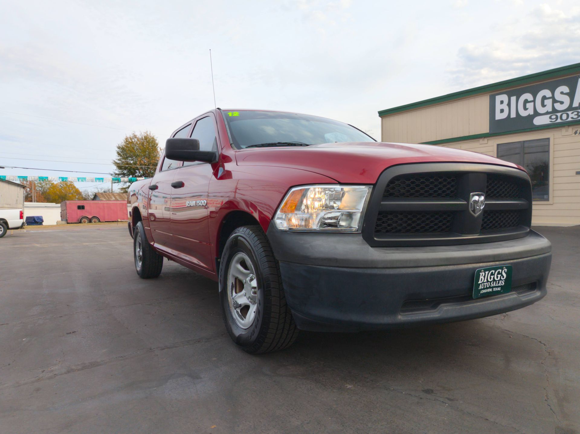 Red Dodge Ram pickup truck parked in front of Biggs Auto building.
