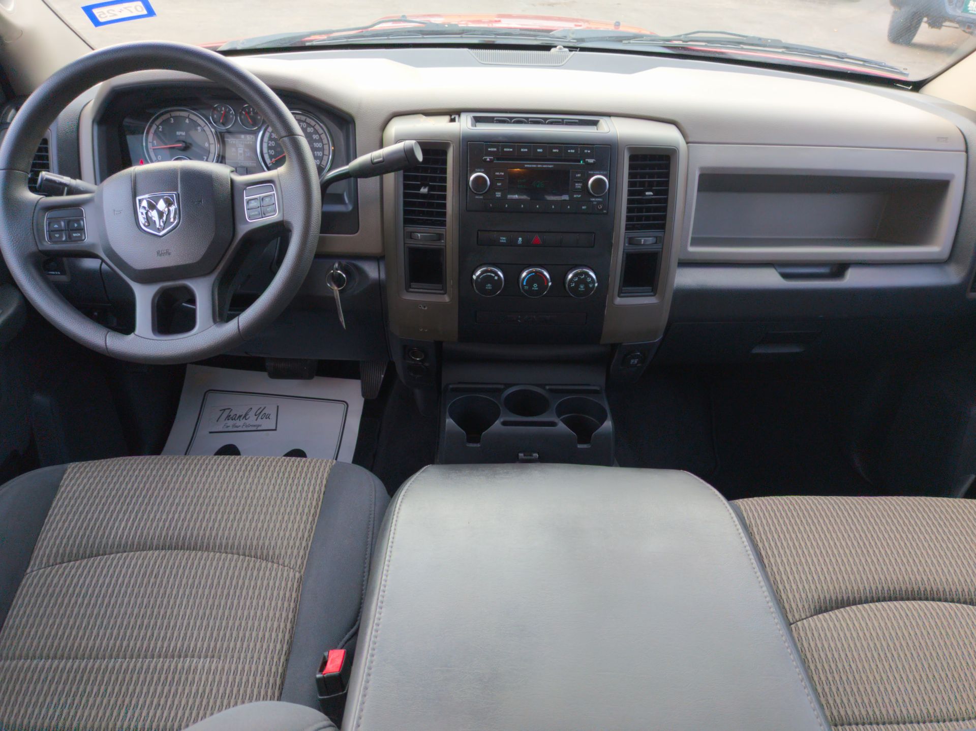 Interior of a Dodge Ram pickup truck. Beige and black dashboard, steering wheel, seats, and center console.
