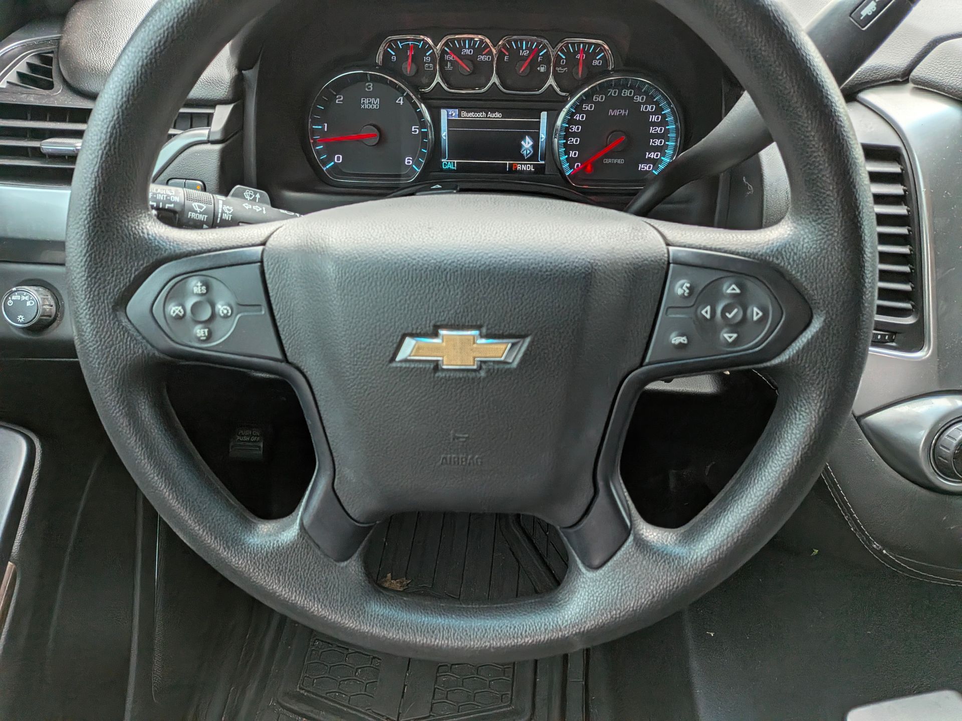 Steering wheel of a Chevrolet vehicle with controls and dashboard gauges visible.