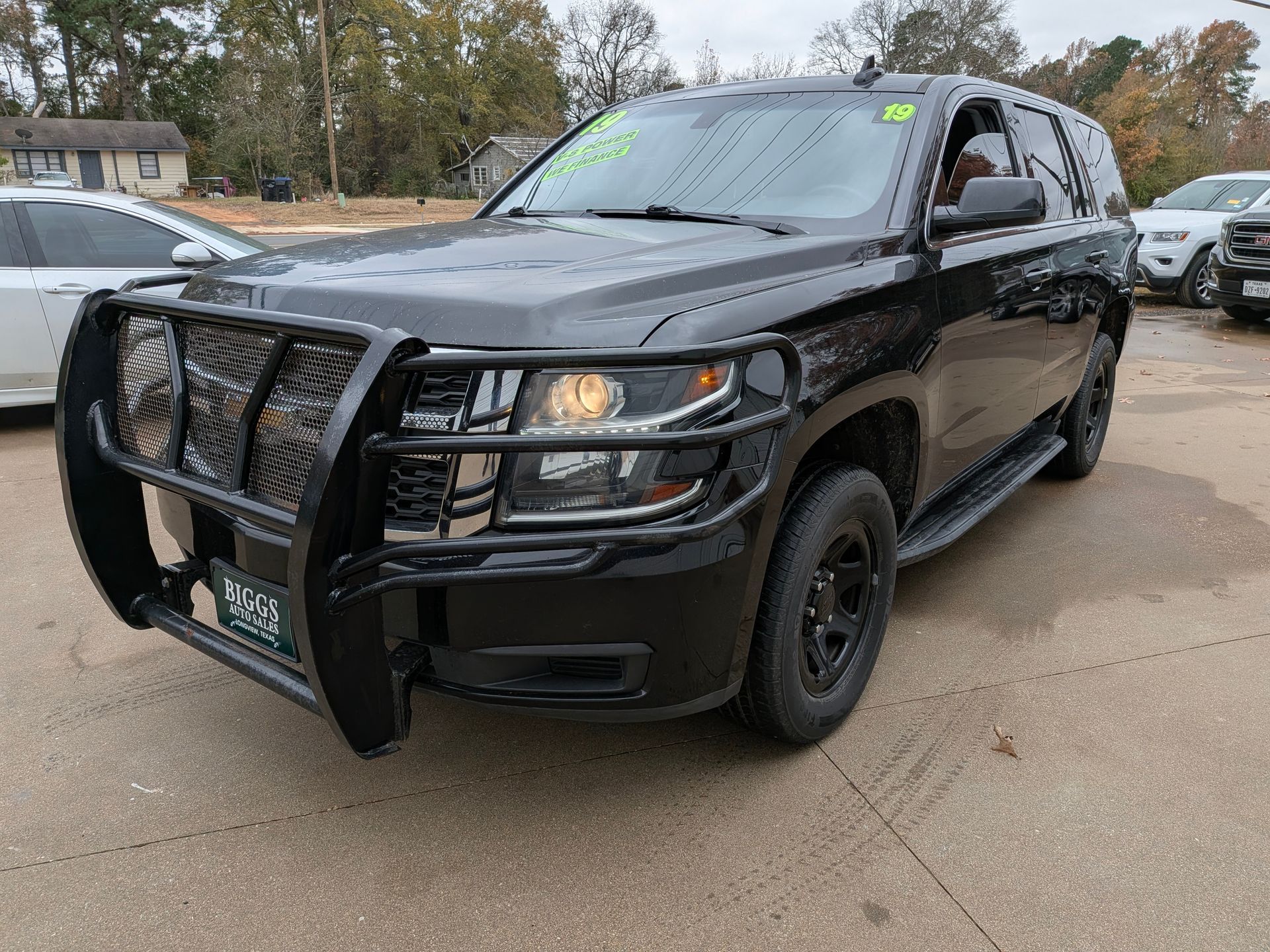 Black SUV with a front brush guard parked outdoors, in front of a car dealership.