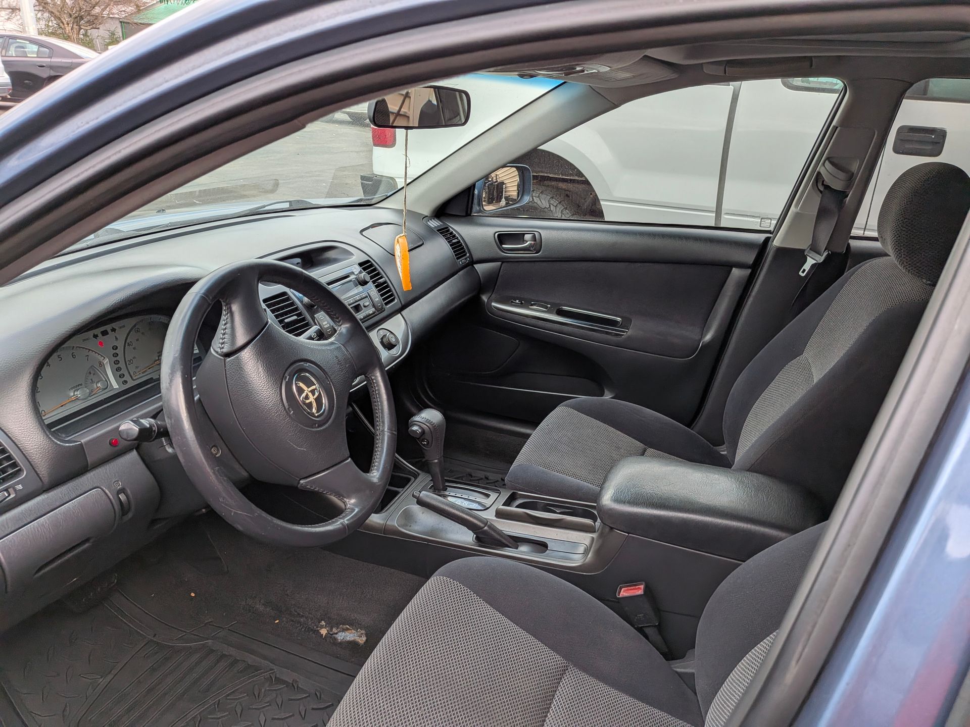 Interior of a blue Toyota Camry. Black and gray seats, dashboard, and steering wheel.