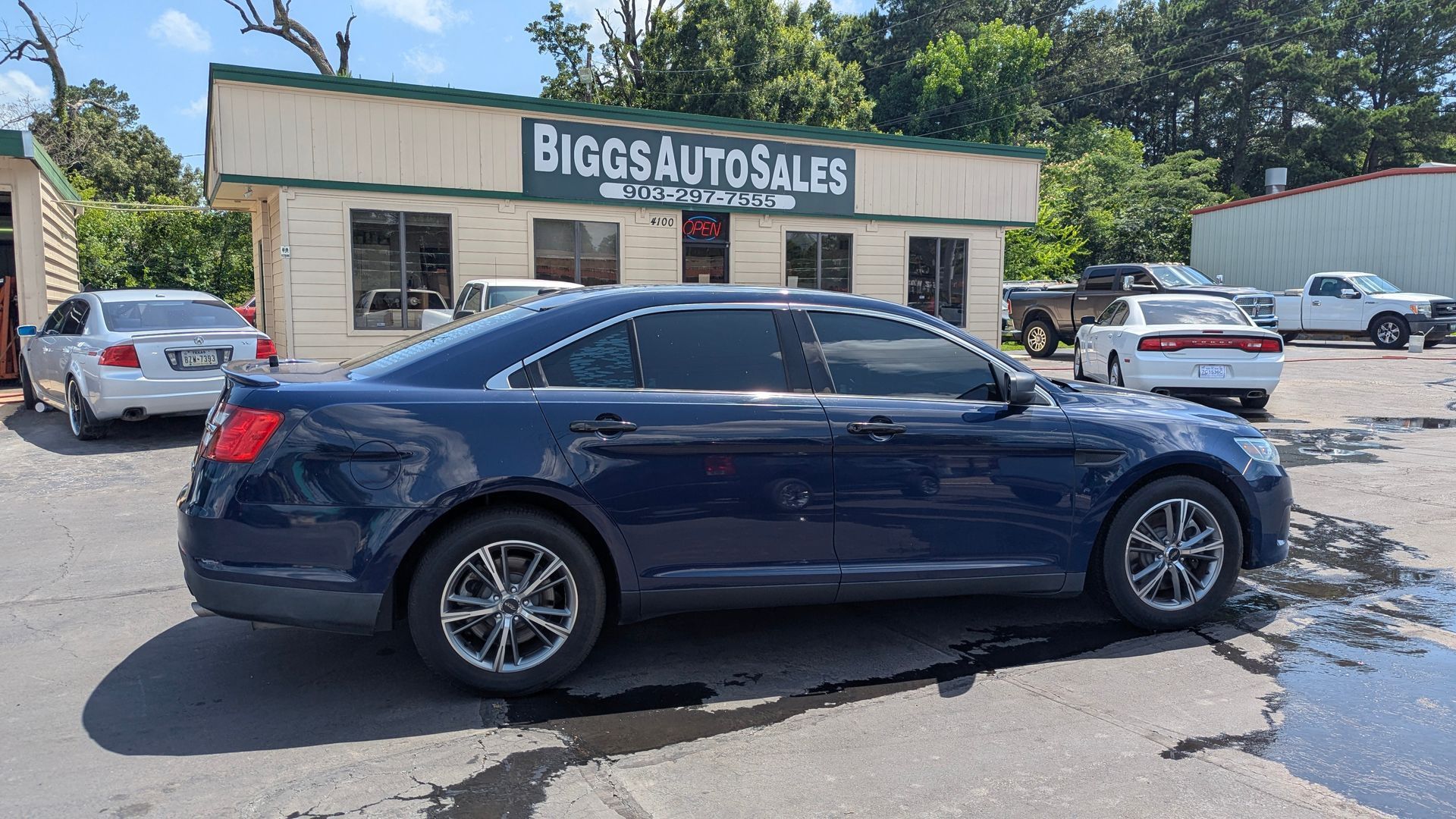 Dark blue car parked at Biggs Auto Sales, exterior shot of a car dealership.