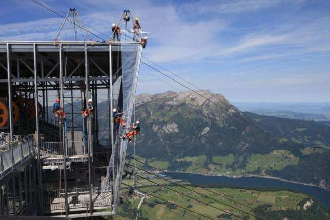 A group of people are working on a building on top of a mountain.