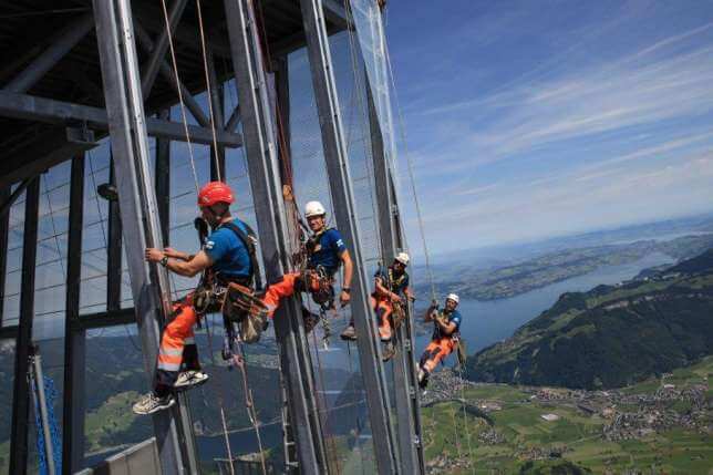 A group of men are climbing a building with a view of a lake.