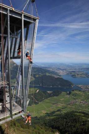 A building is being built on top of a mountain overlooking a lake.