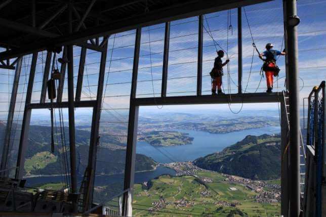 A couple of people standing on top of a building overlooking a lake.