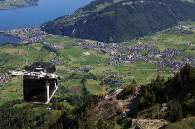 A cable car is going down a mountain overlooking a city.