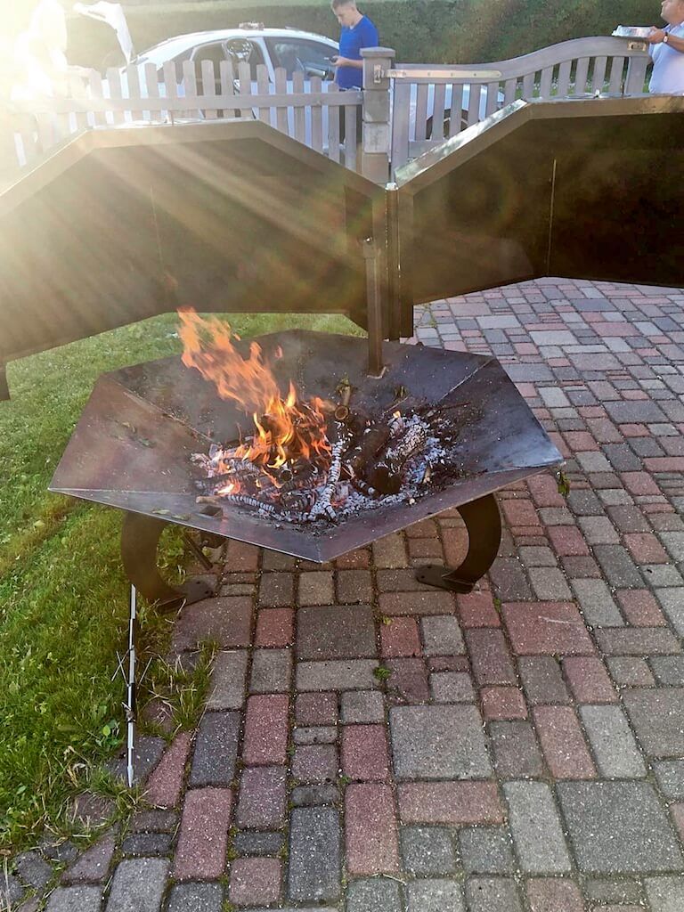 A fire pit is sitting on a brick sidewalk.