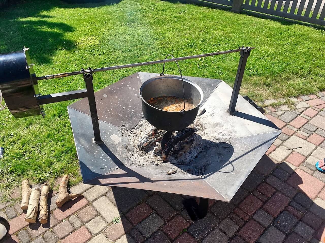 A pot of food is cooking over a fire pit.