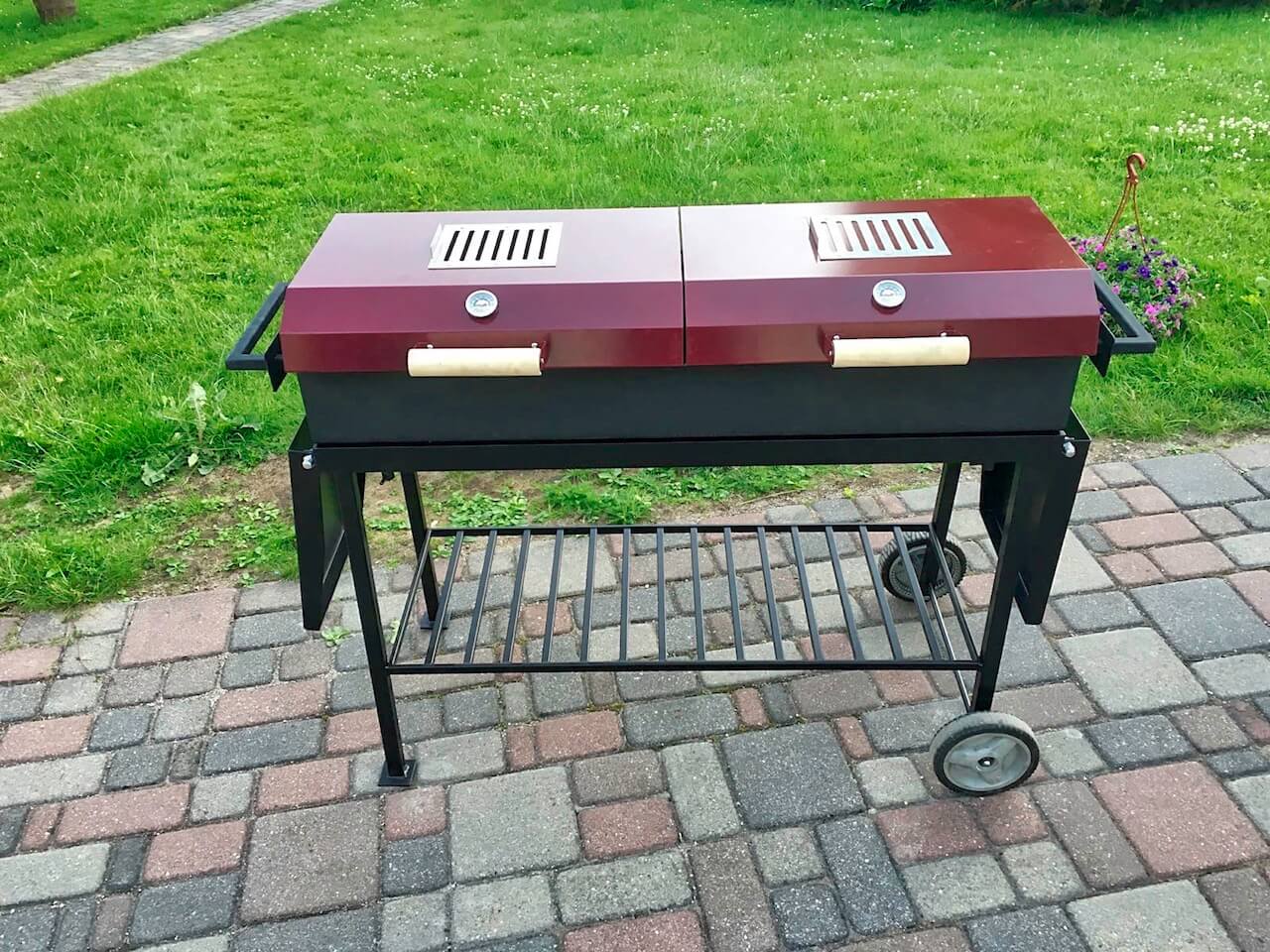 A large barbecue grill is sitting on a brick patio.