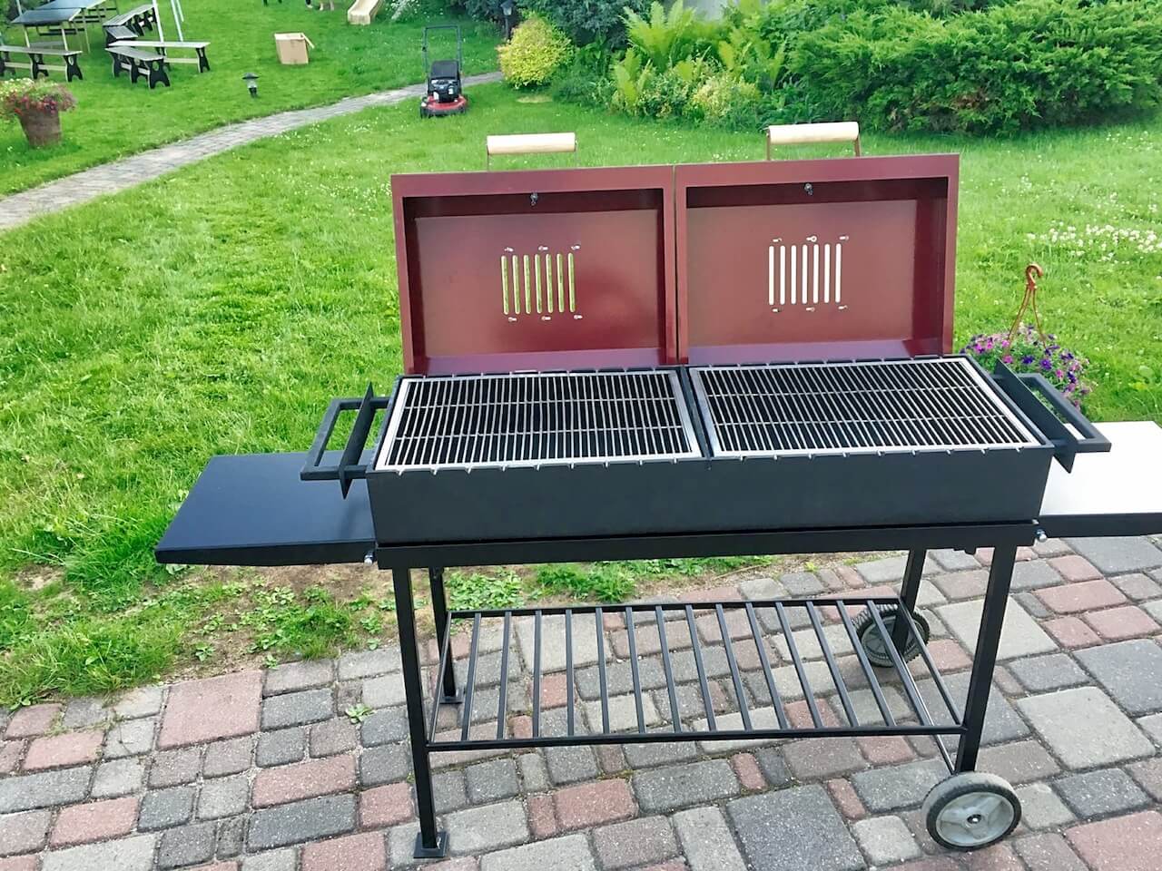 A grill is sitting on a brick patio with the lid open.