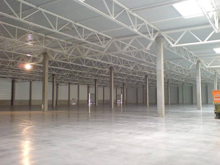 An empty warehouse with a concrete floor and a white roof.