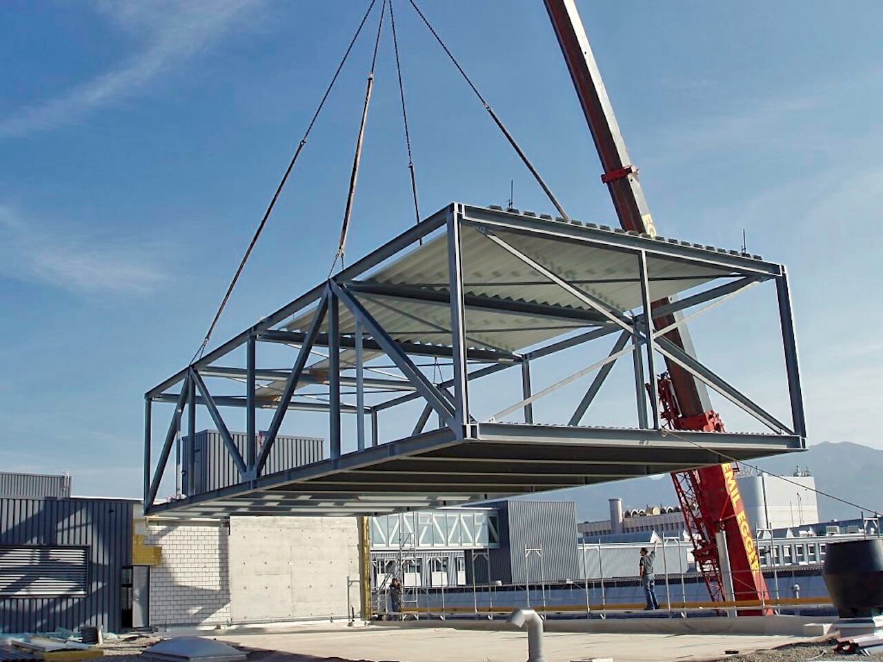 A large metal structure is being lifted by a crane