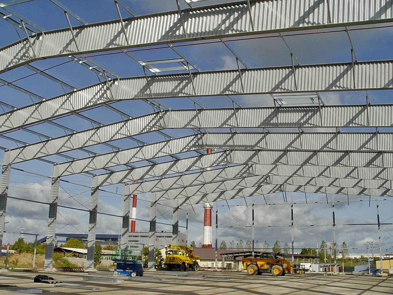 A large metal structure is being built with a blue sky in the background
