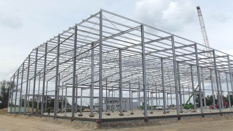 A large metal building under construction with a crane in the background.