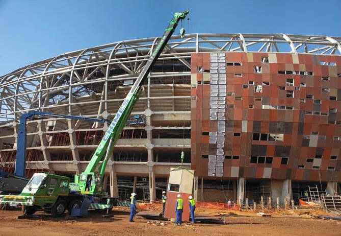 A green crane is being used to lift a building