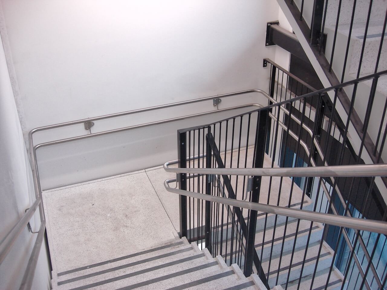 A staircase with a metal railing and a white wall