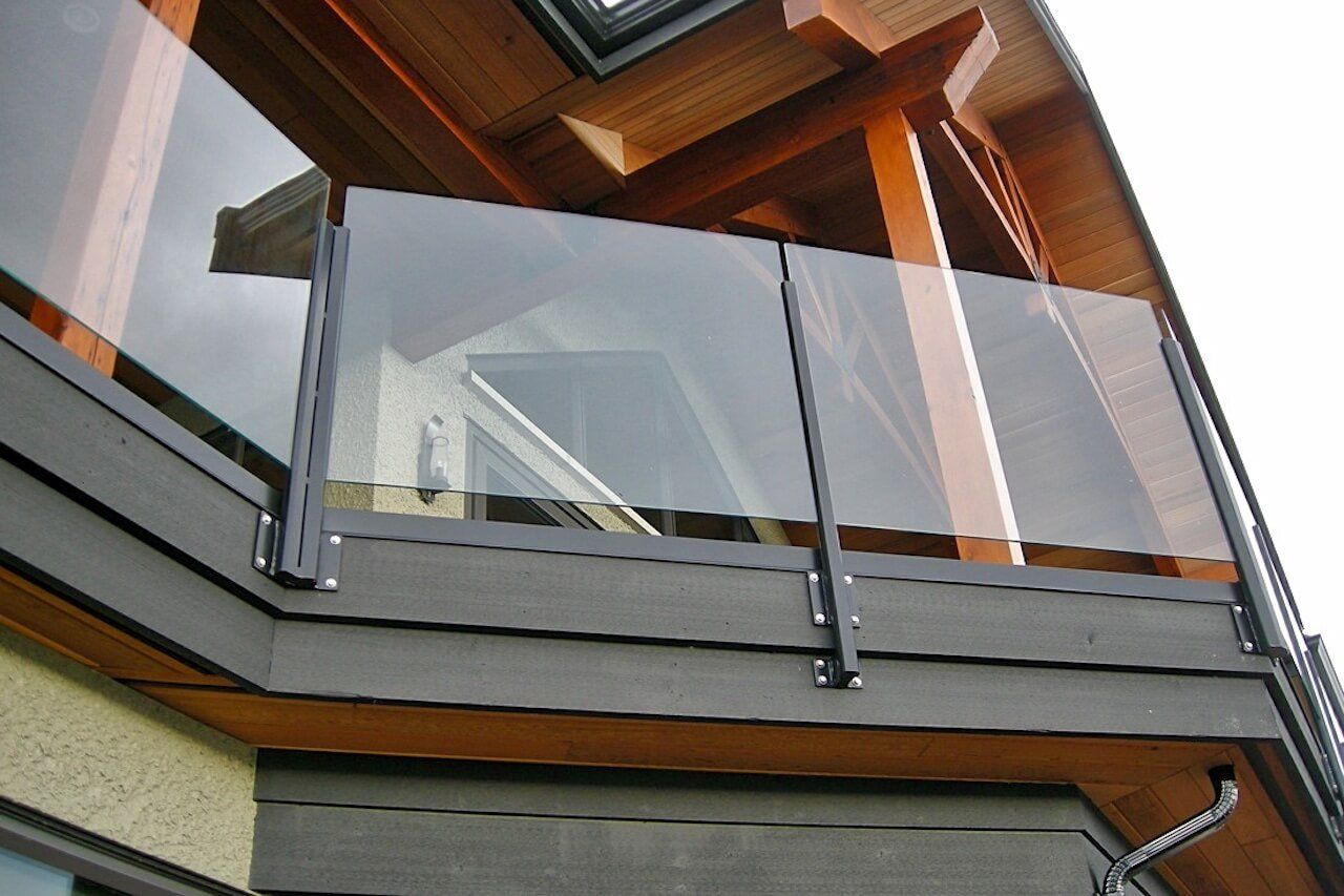 A balcony with a clear glass railing on the side of a building