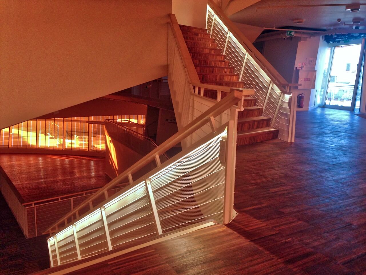 A metal staircase with a white railing and a wooden floor