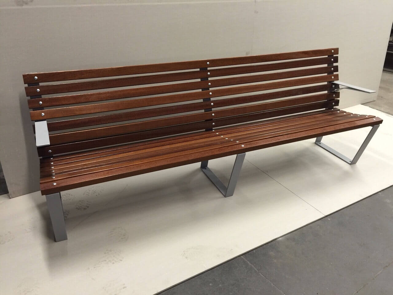 A wooden bench with a metal frame is sitting on a tiled floor.