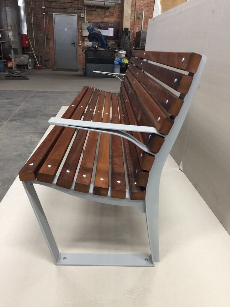 A wooden bench with white arm rests is sitting on a white table.