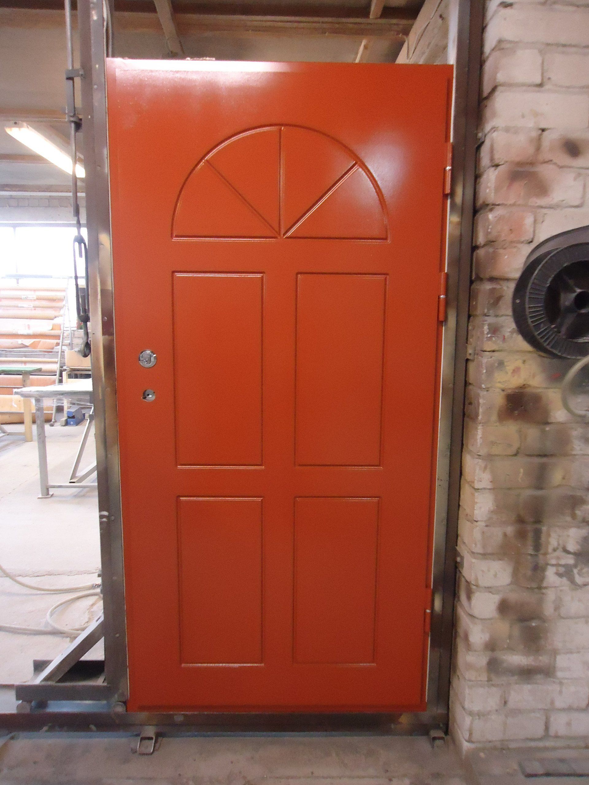 A red door is sitting in front of a brick wall
