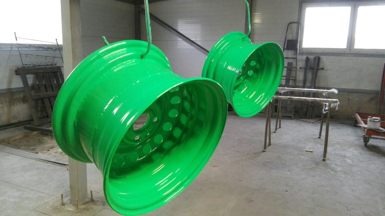 Two green wheels are hanging from a metal pole in a room.