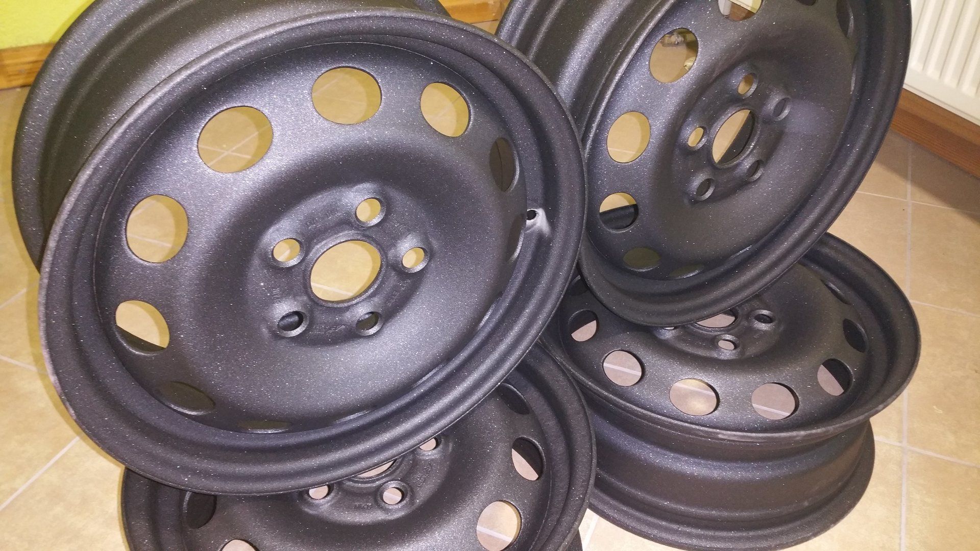 A bunch of black wheels are stacked on top of each other on the floor.